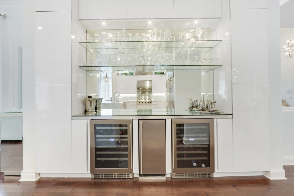 This is an example of an expansive modern single-wall wet bar in Miami with glass-front cabinets, grey cabinets, glass benchtops and mirror splashback.