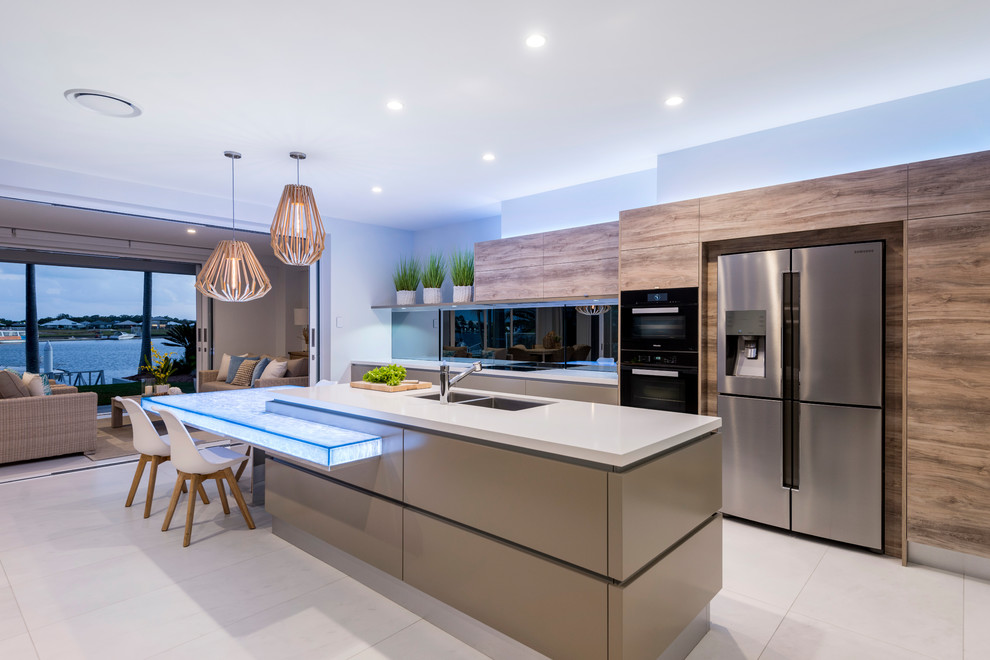 Large contemporary galley open plan kitchen in Brisbane with a double-bowl sink, flat-panel cabinets, cement tiles, with island, beige floor, beige benchtop, medium wood cabinets, black splashback and stainless steel appliances.