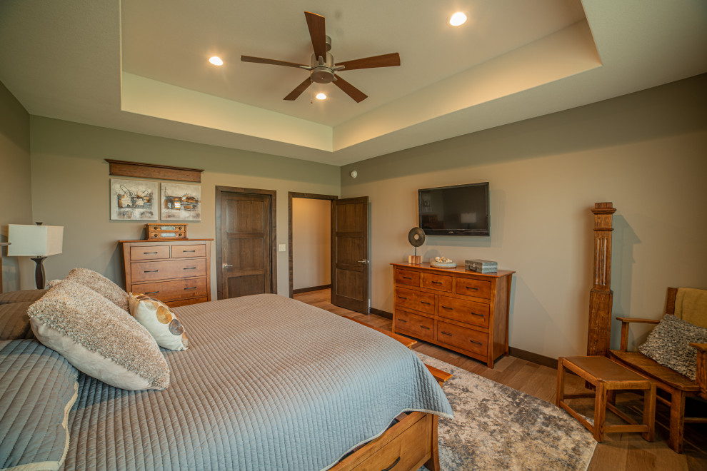 Example of a transitional master medium tone wood floor, beige floor and tray ceiling bedroom design with beige walls
