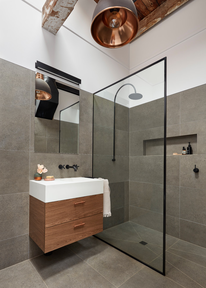 Inspiration for a small industrial 3/4 bathroom in Melbourne with flat-panel cabinets, dark wood cabinets, an open shower, a one-piece toilet, gray tile, porcelain tile, porcelain floors, an integrated sink, solid surface benchtops, grey floor, an open shower and a freestanding tub.
