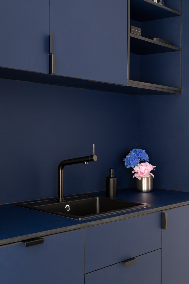 This is an example of a mid-sized industrial single-wall open plan kitchen in Madrid with a drop-in sink, shaker cabinets, blue cabinets, blue splashback, black appliances, concrete floors, with island, white floor and blue benchtop.
