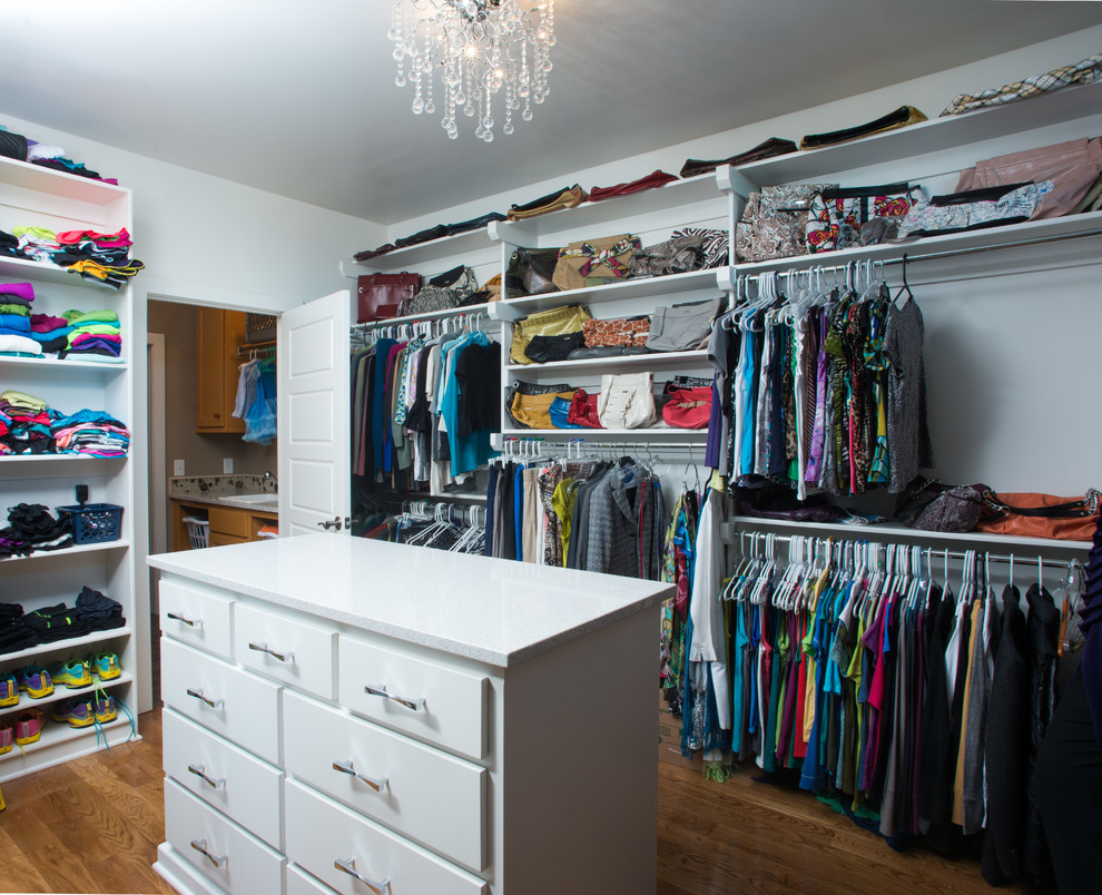 This is an example of a large transitional gender-neutral walk-in wardrobe in Kansas City with flat-panel cabinets, white cabinets and dark hardwood floors.