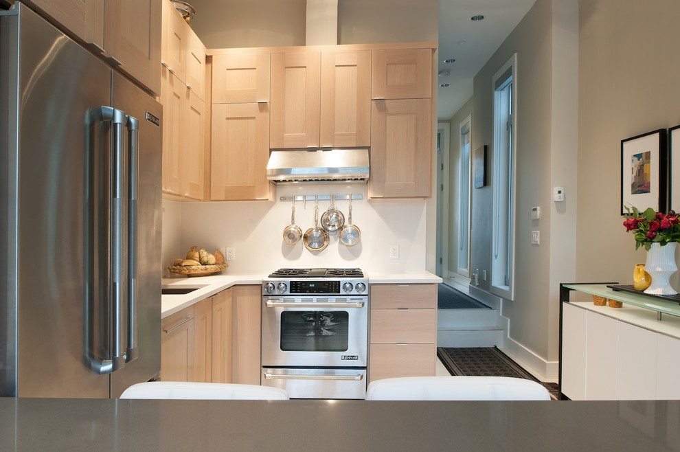 Contemporary kitchen in Vancouver with an undermount sink, light wood cabinets, quartz benchtops, white splashback and stainless steel appliances.
