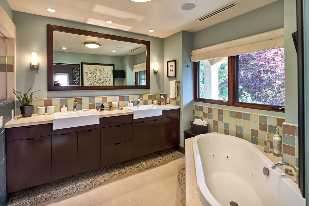 Mid-sized mediterranean master bathroom in San Francisco with flat-panel cabinets, beige cabinets, a drop-in tub, an alcove shower, a two-piece toilet, multi-coloured tile, glass tile, blue walls, limestone floors, an undermount sink and limestone benchtops.