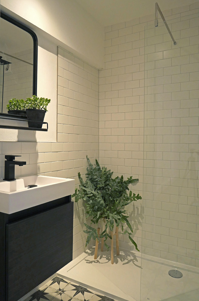 Photo of a small contemporary kids bathroom in Sussex with flat-panel cabinets, black cabinets, an open shower, a one-piece toilet, white tile, ceramic tile, white walls, ceramic floors, a wall-mount sink, multi-coloured floor and an open shower.