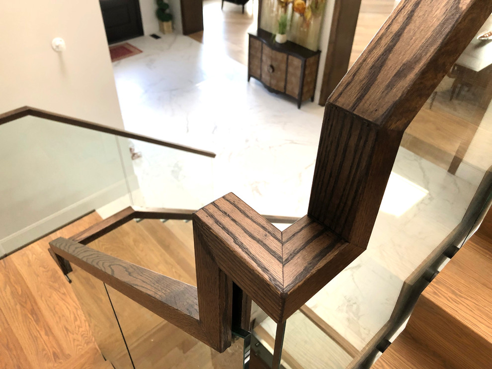 This is an example of a mid-sized modern wood u-shaped staircase in Toronto with wood risers and glass railing.