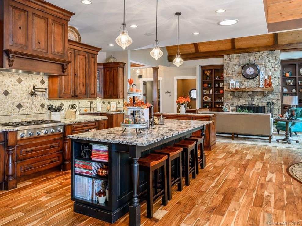 Inspiration for a rustic medium tone wood floor open concept kitchen remodel with a farmhouse sink, dark wood cabinets, granite countertops, beige backsplash, an island and white countertops