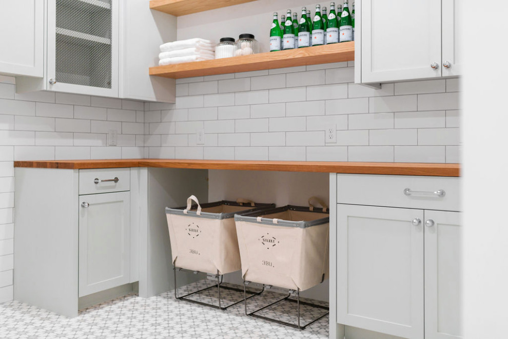 This is an example of a large country u-shaped dedicated laundry room in Phoenix with a farmhouse sink, shaker cabinets, blue cabinets, wood benchtops, white walls, concrete floors, a side-by-side washer and dryer, grey floor and brown benchtop.