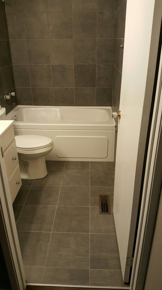 Example of a mid-sized transitional 3/4 brown tile and ceramic tile ceramic tile and brown floor alcove bathtub design with flat-panel cabinets, white cabinets, a two-piece toilet, brown walls and solid surface countertops