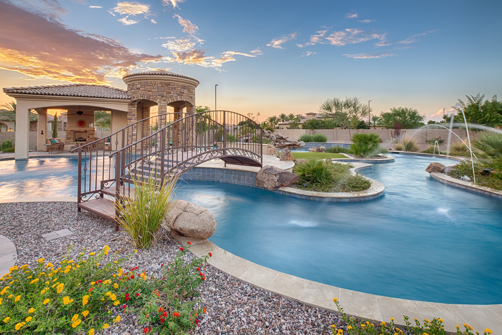This is an example of a large mediterranean backyard custom-shaped natural pool in Phoenix with concrete pavers.