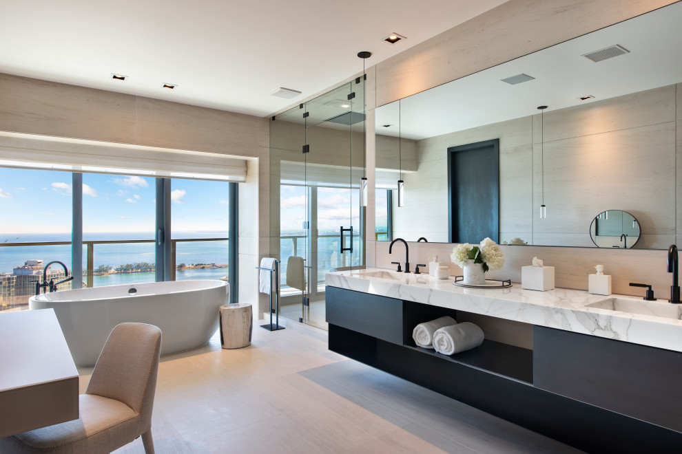 Inspiration for a contemporary master bathroom in Miami with flat-panel cabinets, black cabinets, a freestanding tub, beige tile, light hardwood floors, an integrated sink, beige floor, white benchtops, a double vanity and a floating vanity.