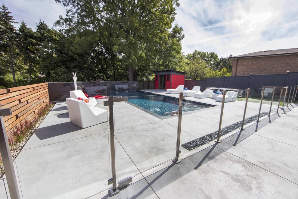 Inspiration for a mid-sized backyard rectangular lap pool in Toronto with a pool house and stamped concrete.