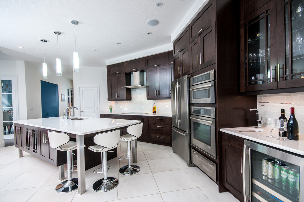 Enclosed kitchen - mid-sized transitional single-wall porcelain tile enclosed kitchen idea in Toronto with an undermount sink, shaker cabinets, dark wood cabinets, white backsplash, subway tile backsplash, stainless steel appliances, an island and solid surface countertops