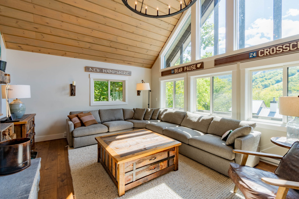 Uriges Wohnzimmer mit grauer Wandfarbe, braunem Holzboden, Kaminumrandung aus Stein, braunem Boden und Holzdielendecke in Burlington