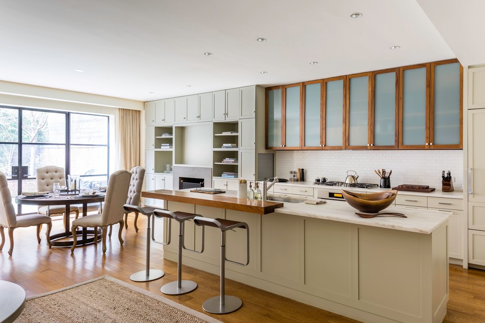 This is an example of a large transitional galley open plan kitchen in Other with an undermount sink, shaker cabinets, white splashback, subway tile splashback, medium hardwood floors, with island, beige cabinets, quartz benchtops and panelled appliances.