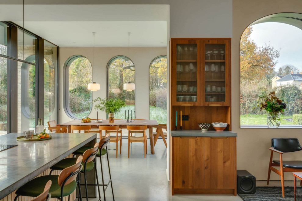 На фото: большая угловая кухня в стиле рустика с обеденным столом, плоскими фасадами, фасадами цвета дерева среднего тона, столешницей из бетона, островом и серой столешницей