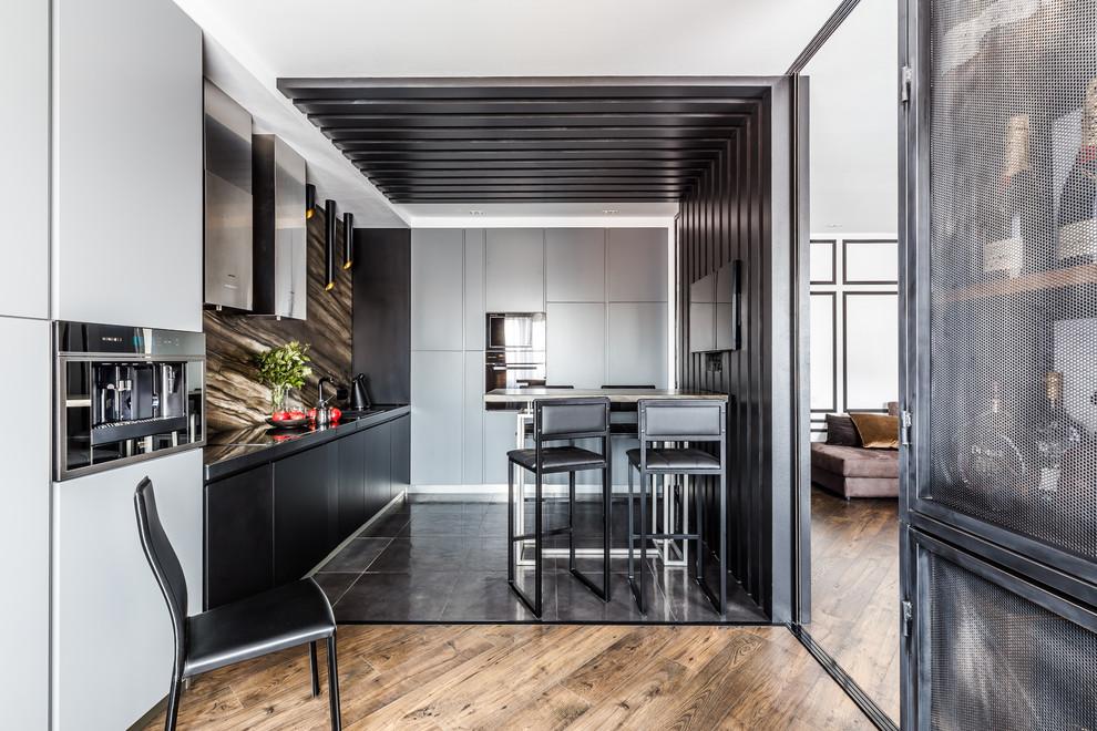 Photo of a large contemporary l-shaped open plan kitchen in Other with a single-bowl sink, flat-panel cabinets, solid surface benchtops, marble splashback, black appliances, porcelain floors, no island, black floor, black cabinets and brown splashback.