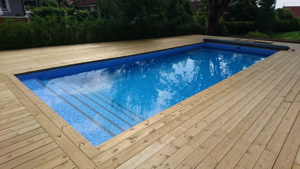 Idéer för att renovera en mellanstor anpassad pool på baksidan av huset, med trädäck