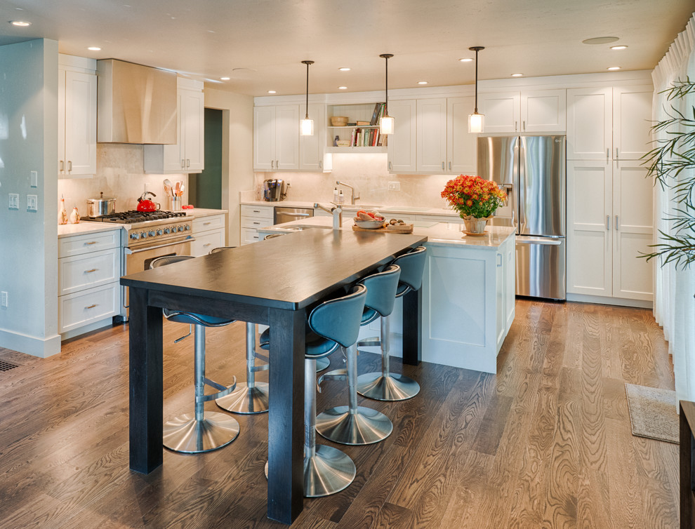 Mid-sized modern l-shaped eat-in kitchen in Denver with a drop-in sink, shaker cabinets, white cabinets, granite benchtops, white splashback, stainless steel appliances, plywood floors and multiple islands.