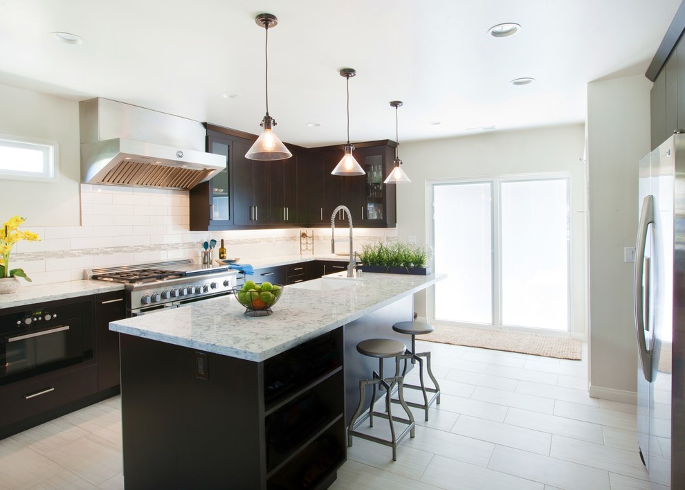 Open concept kitchen - mid-sized transitional u-shaped porcelain tile open concept kitchen idea in Los Angeles with a farmhouse sink, flat-panel cabinets, dark wood cabinets, quartz countertops, white backsplash, subway tile backsplash, stainless steel appliances and an island