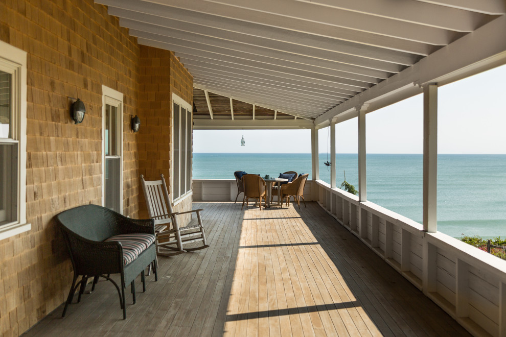 Design ideas for an expansive beach style first floor deck in Boston with a roof extension and wood railing.