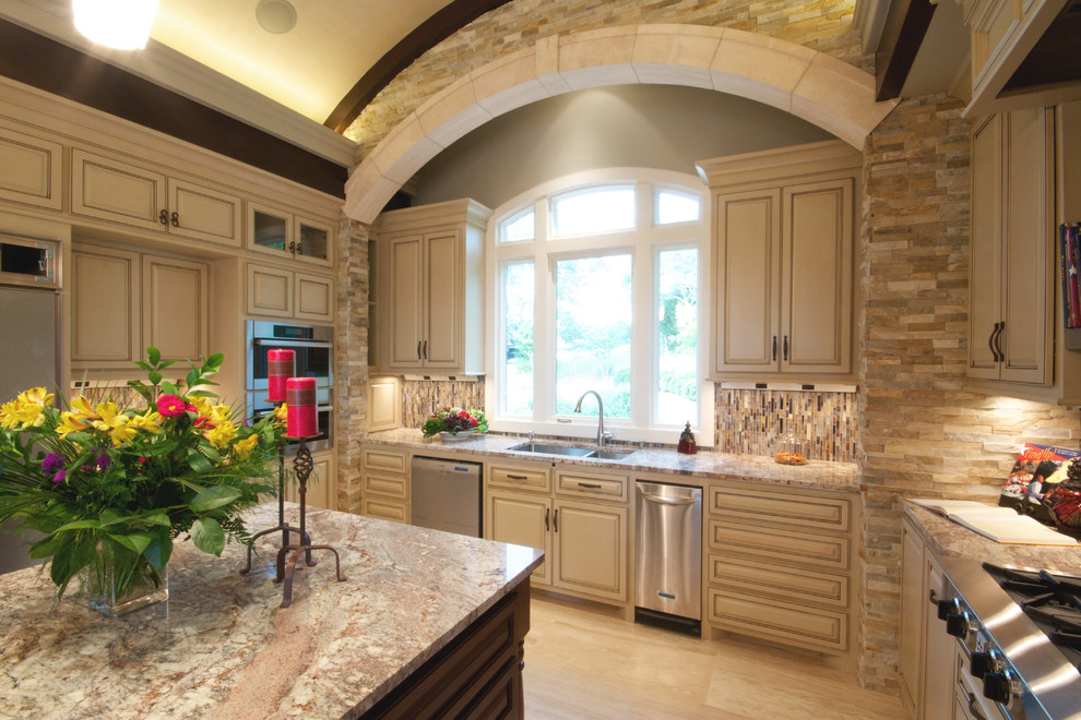 Inspiration for an expansive traditional u-shaped open plan kitchen in Austin with an undermount sink, raised-panel cabinets, distressed cabinets, granite benchtops, multi-coloured splashback, stainless steel appliances and travertine floors.