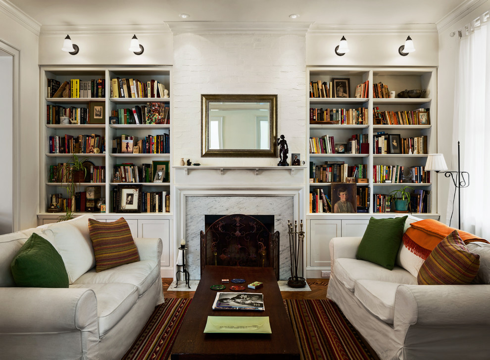 Small contemporary enclosed living room in New York with a library, white walls, medium hardwood floors, a standard fireplace and a stone fireplace surround.