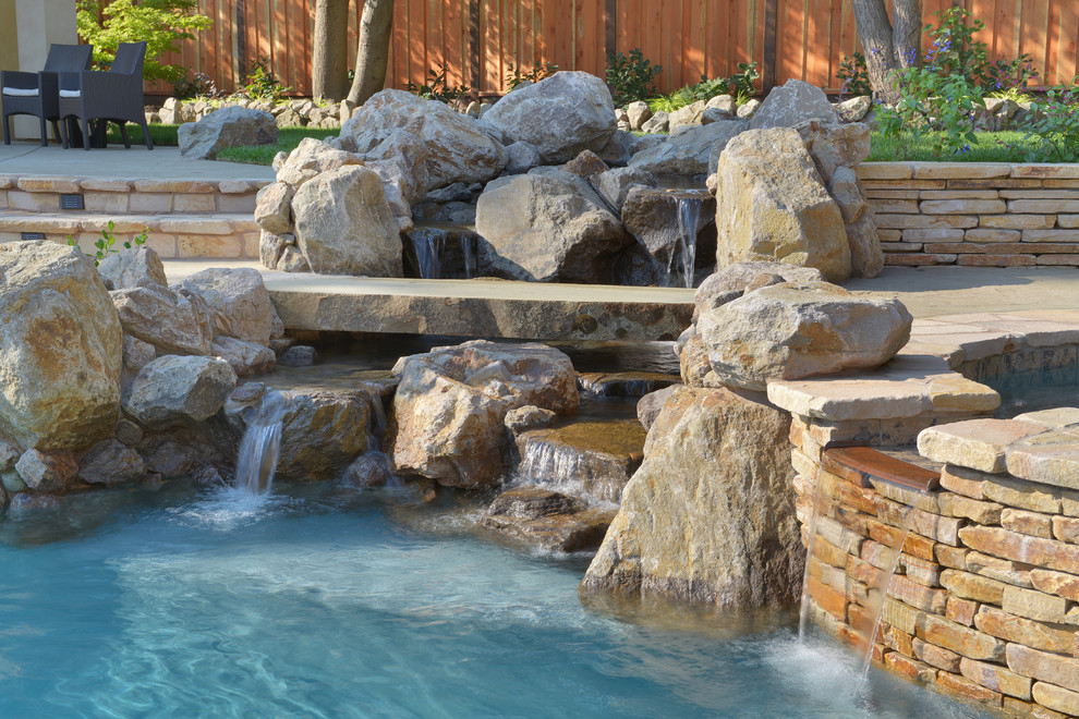 This is an example of an expansive mediterranean backyard custom-shaped lap pool in San Francisco with a water feature and natural stone pavers.
