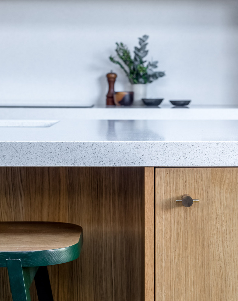 Contemporary kitchen in London with a drop-in sink, flat-panel cabinets, medium wood cabinets, solid surface benchtops, white splashback, engineered quartz splashback, coloured appliances, terrazzo floors, with island, multi-coloured floor, white benchtop and vaulted.