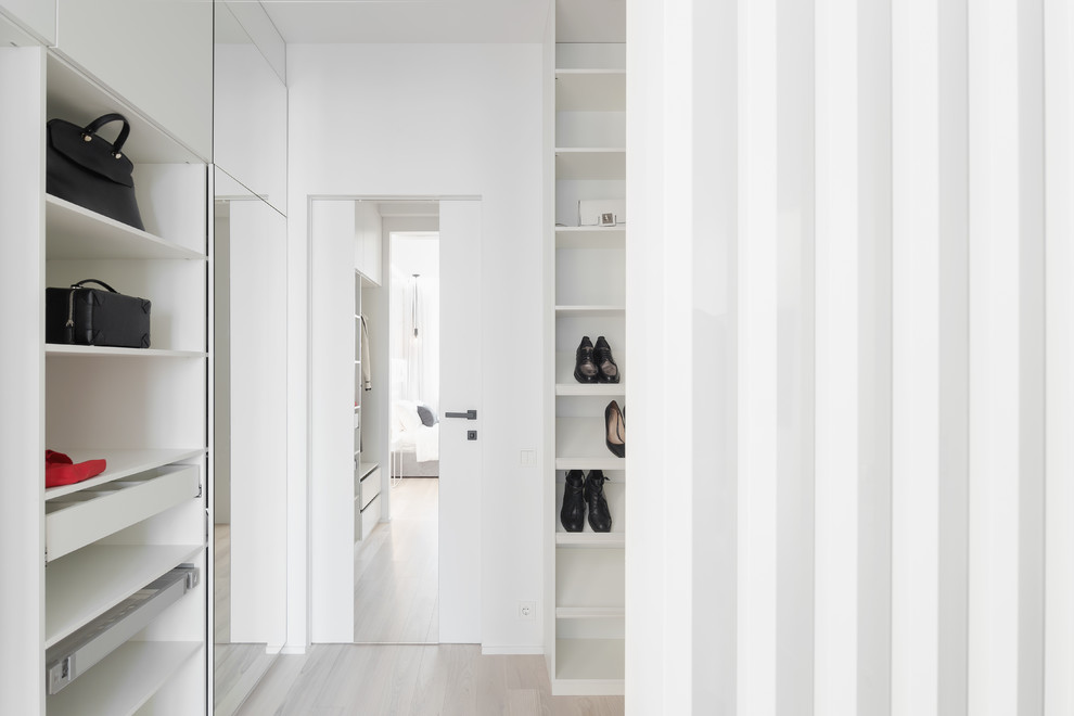 Design ideas for a small contemporary women's built-in wardrobe in Moscow with open cabinets and light hardwood floors.