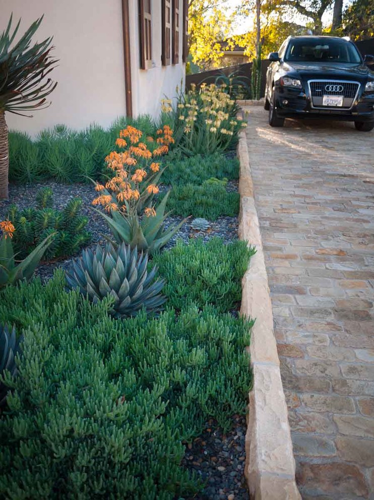 Inspiration for a mediterranean front yard driveway in Santa Barbara with natural stone pavers.