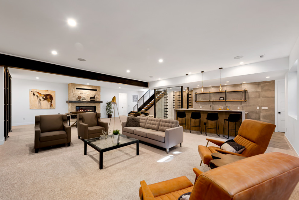 Inspiration for a large modern fully buried basement in Denver with a home bar, white walls, carpet, a standard fireplace, a stone fireplace surround, beige floor and exposed beam.