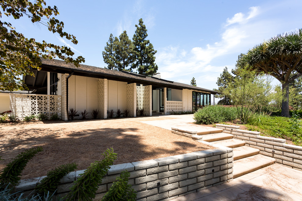 Large midcentury one-storey white house exterior in Orange County with a gable roof and a shingle roof.