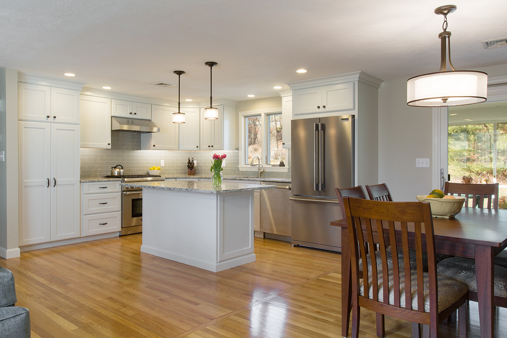 Example of a mid-sized transitional l-shaped medium tone wood floor eat-in kitchen design in Boston with an undermount sink, recessed-panel cabinets, white cabinets, quartz countertops, green backsplash, ceramic backsplash, stainless steel appliances and an island