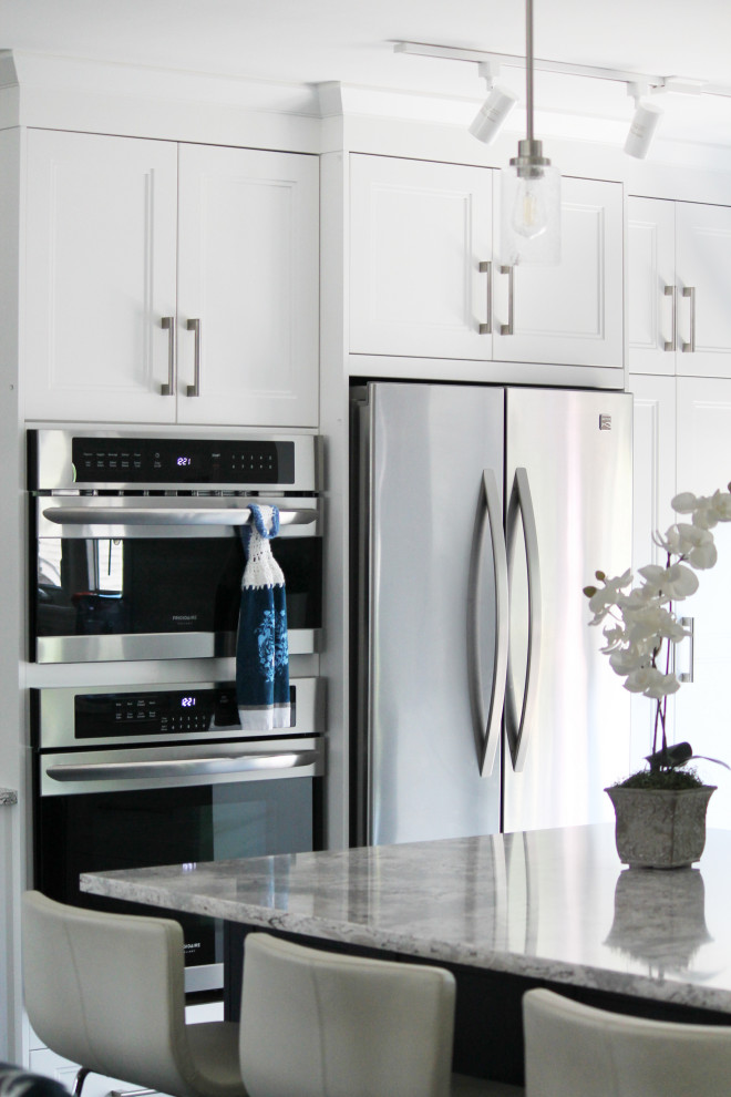 Example of a large transitional u-shaped eat-in kitchen design with shaker cabinets, white cabinets, quartz countertops, white backsplash, subway tile backsplash, stainless steel appliances, an island and gray countertops