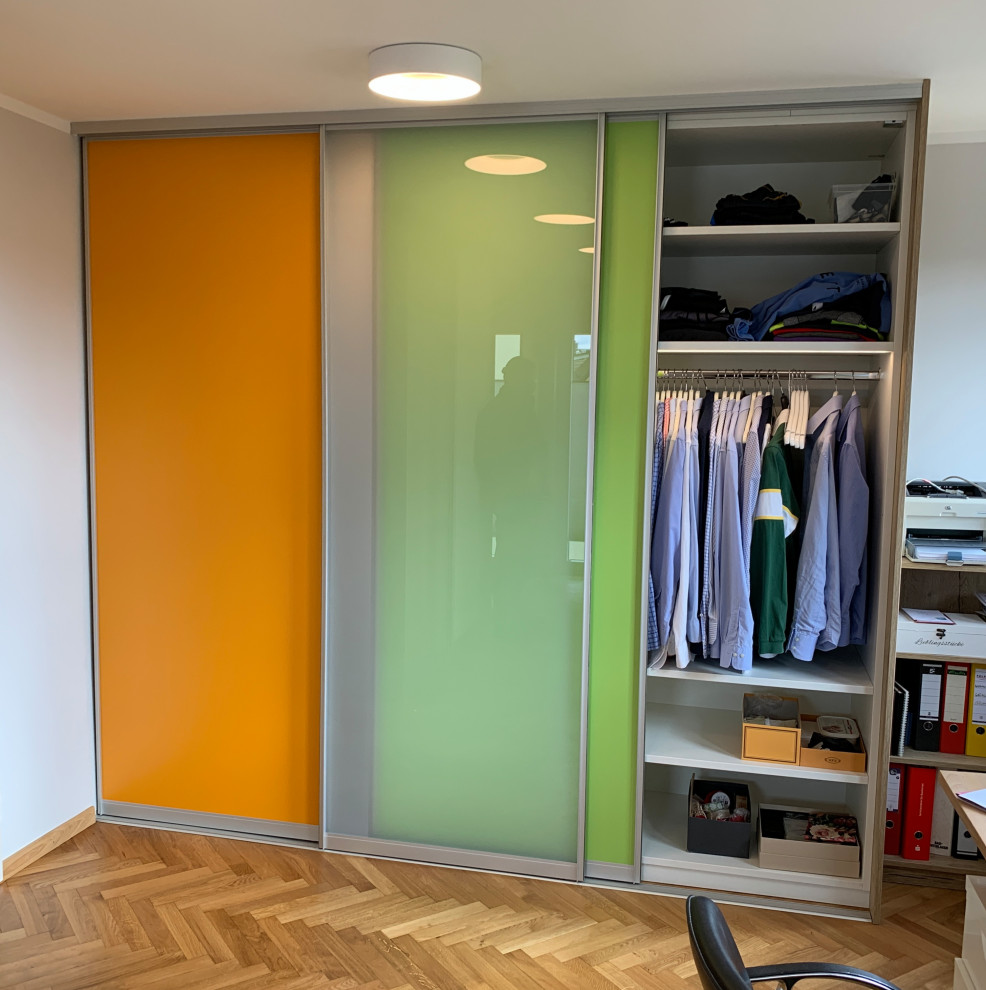 Idée de décoration pour un grand dressing room design neutre avec parquet clair et un sol marron.