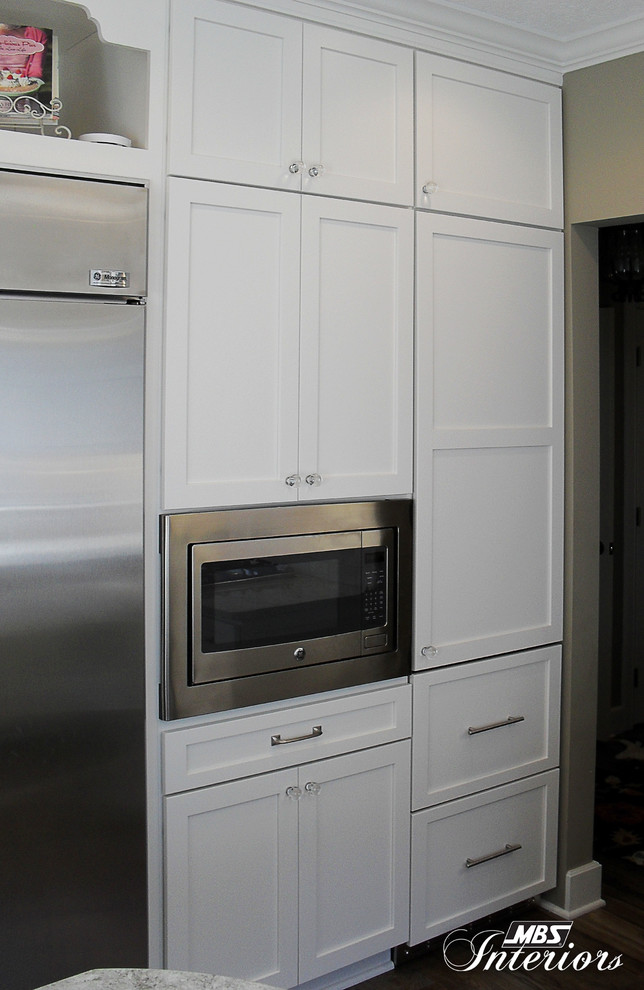Inspiration for a mid-sized transitional u-shaped medium tone wood floor eat-in kitchen remodel with a farmhouse sink, shaker cabinets, white cabinets, quartzite countertops, white backsplash, subway tile backsplash, stainless steel appliances and an island