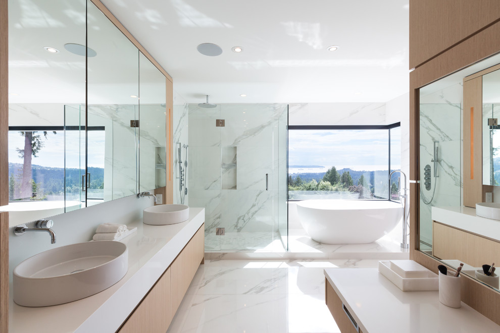 Large contemporary master bathroom in Vancouver with flat-panel cabinets, light wood cabinets, a freestanding tub, white tile, stone slab, a vessel sink, a hinged shower door, white benchtops, a curbless shower, a one-piece toilet, white walls, marble floors, engineered quartz benchtops, white floor and a niche.