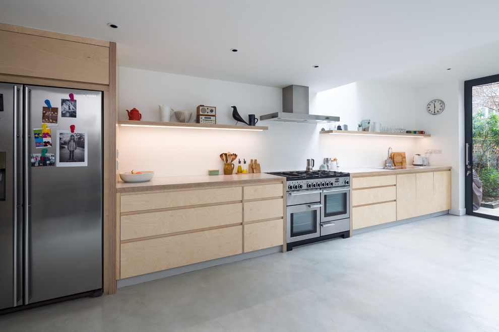 This is an example of a mid-sized contemporary single-wall open plan kitchen in London with flat-panel cabinets, light wood cabinets, laminate benchtops, no island and white benchtop.