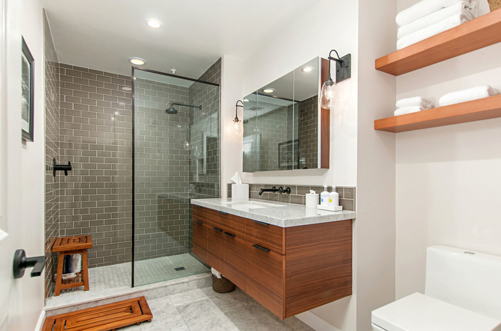 Small midcentury master bathroom in San Diego with flat-panel cabinets, medium wood cabinets, an open shower, a two-piece toilet, beige tile, glass tile, white walls, marble floors, an undermount sink, marble benchtops, white floor and an open shower.