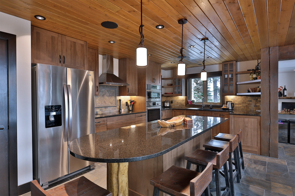 Inspiration for a country l-shaped open plan kitchen in Vancouver with a double-bowl sink, shaker cabinets, medium wood cabinets, granite benchtops, multi-coloured splashback, slate splashback, stainless steel appliances, slate floors, with island, grey floor, black benchtop and wood.