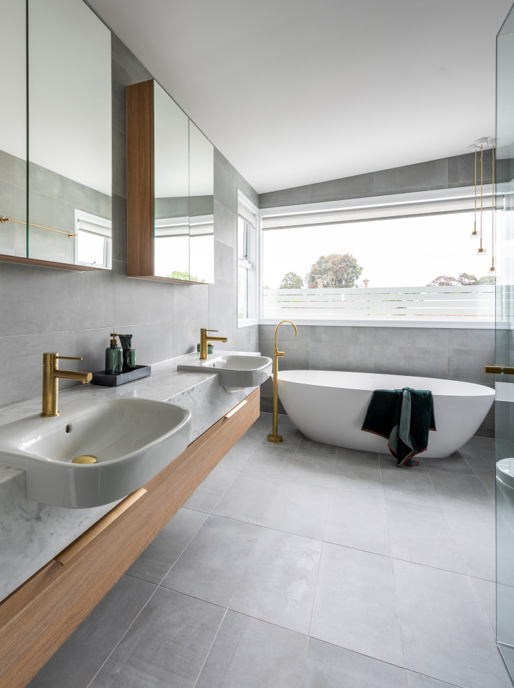 Large contemporary master bathroom in Melbourne with flat-panel cabinets, a freestanding tub, white tile, ceramic floors, grey floor, grey benchtops, a double vanity, a floating vanity, medium wood cabinets, a drop-in sink and vaulted.