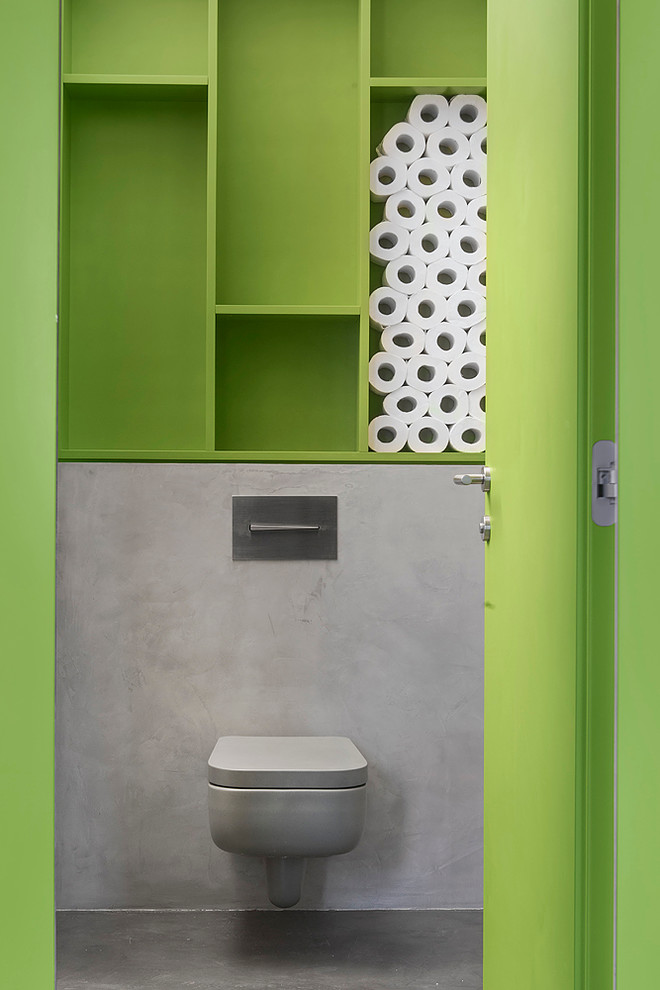 Photo of an industrial powder room in Moscow with a wall-mount toilet, green walls and grey floor.