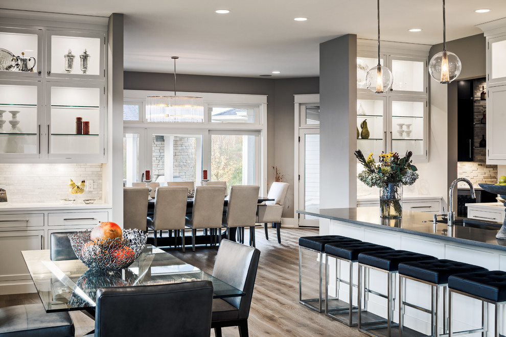 Large transitional u-shaped eat-in kitchen in Grand Rapids with recessed-panel cabinets, grey cabinets, quartzite benchtops, beige splashback, matchstick tile splashback, stainless steel appliances, light hardwood floors and with island.