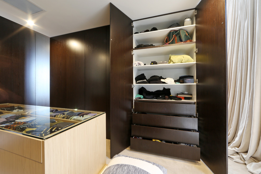 This is an example of a contemporary gender-neutral walk-in wardrobe in Melbourne with dark wood cabinets and carpet.