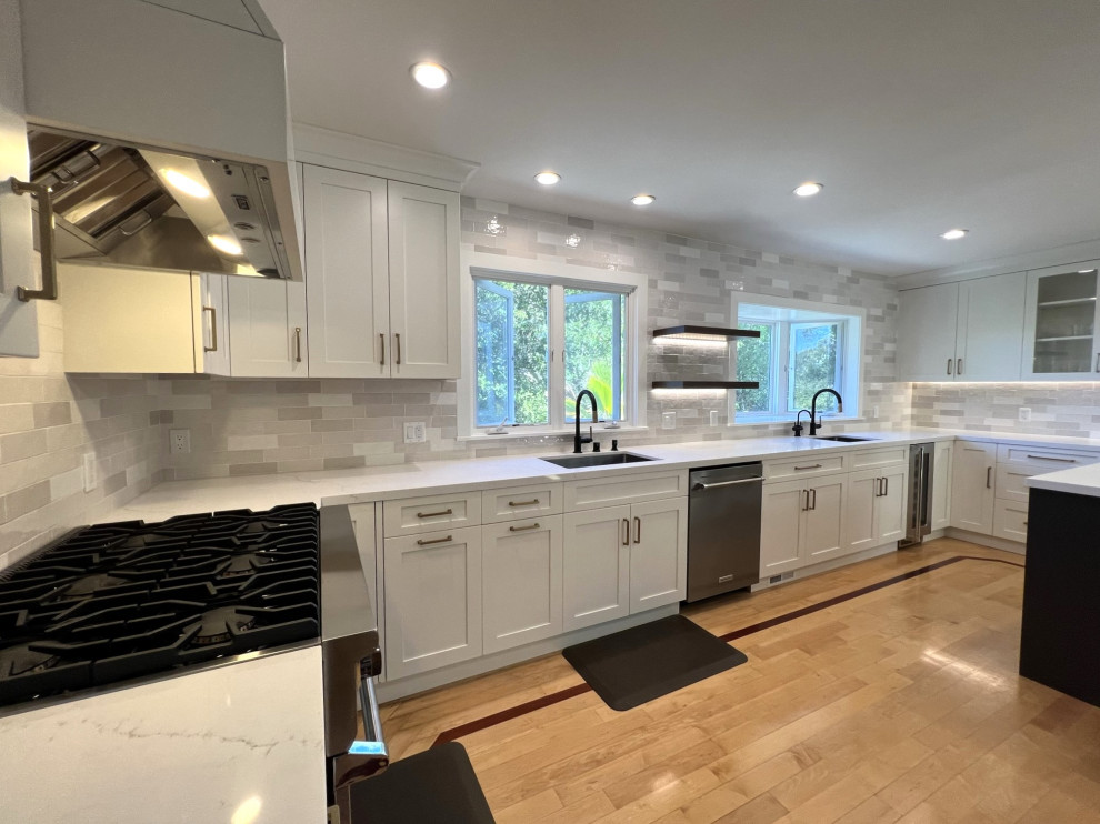 Photo of a large traditional u-shaped kitchen/diner in San Francisco with a submerged sink, shaker cabinets, white cabinets, engineered stone countertops, grey splashback, ceramic splashback, stainless steel appliances, medium hardwood flooring, an island, yellow floors and white worktops.