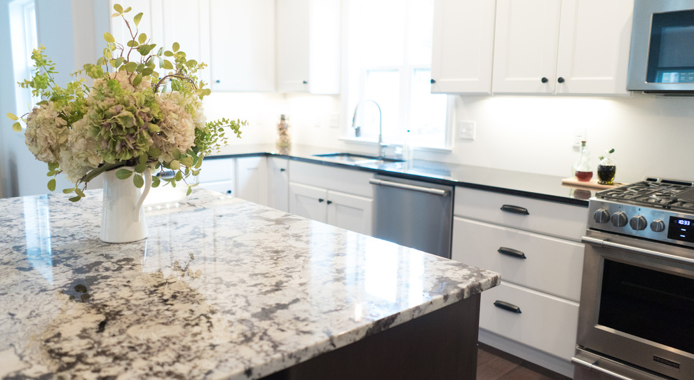 Example of a mid-sized transitional l-shaped dark wood floor open concept kitchen design with an undermount sink, shaker cabinets, white cabinets, granite countertops, gray backsplash, stainless steel appliances and an island
