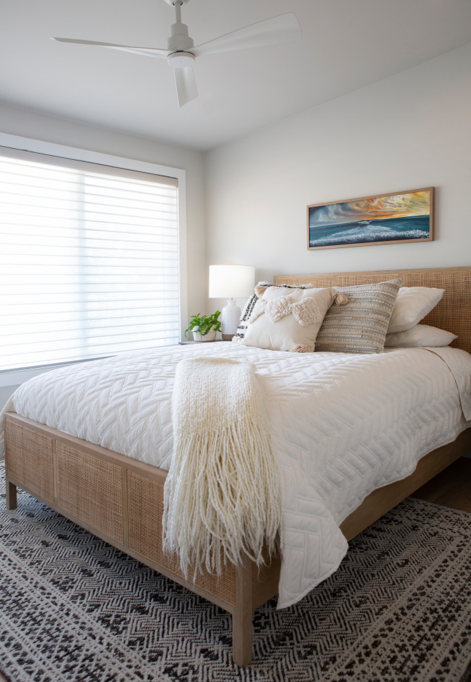 Design ideas for a small beach style guest bedroom in Orange County with white walls and light hardwood floors.