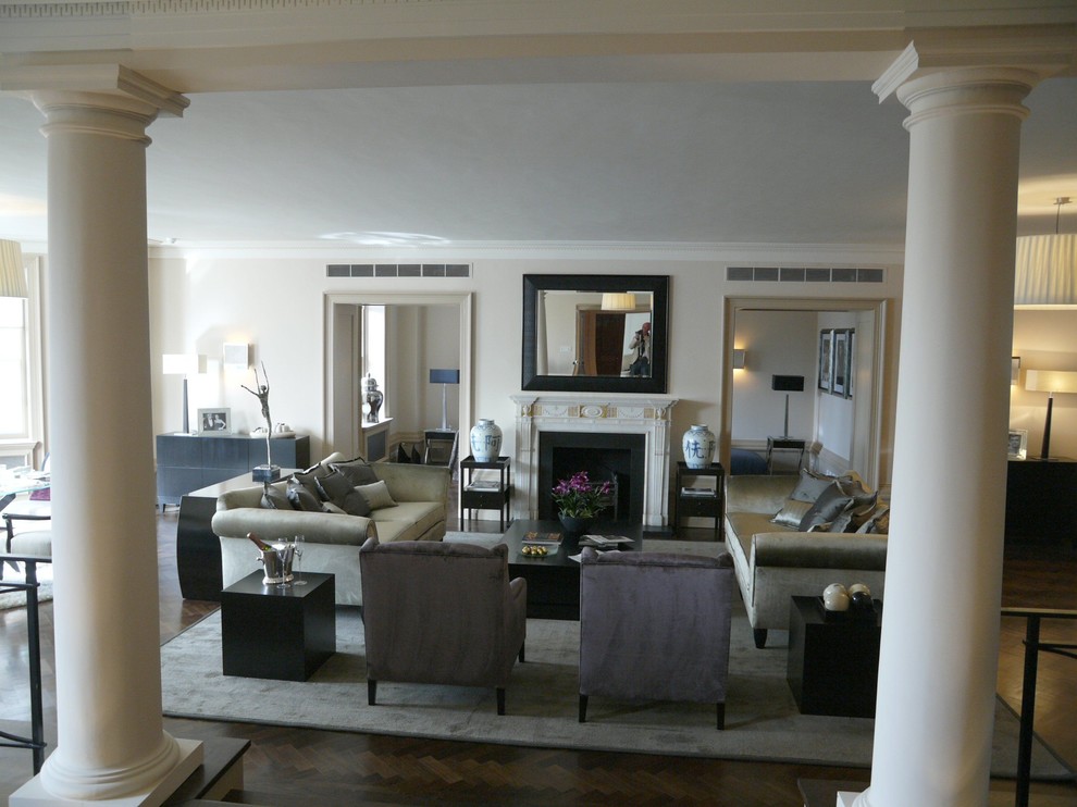 Photo of a mid-sized transitional formal open concept living room in Other with beige walls, medium hardwood floors, a standard fireplace, a plaster fireplace surround and no tv.