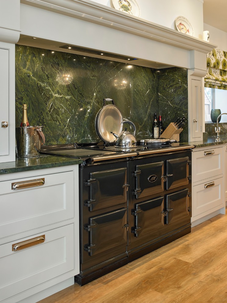 Design ideas for a large traditional single-wall eat-in kitchen in Other with a farmhouse sink, beaded inset cabinets, green cabinets, granite benchtops, green splashback, stone slab splashback, black appliances, medium hardwood floors, with island and green benchtop.